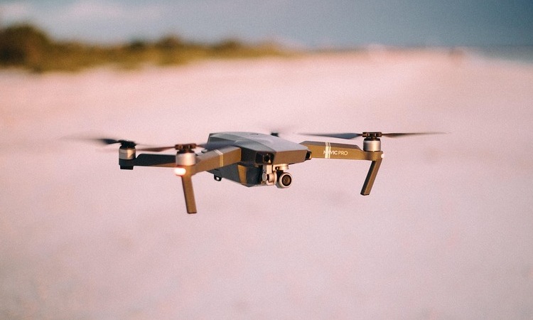 A quadcopter drone flying over an open outdoor area.